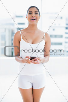 Laughing toned brunette holding smartphone