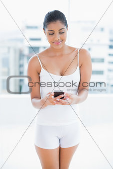 Content toned brunette holding smartphone