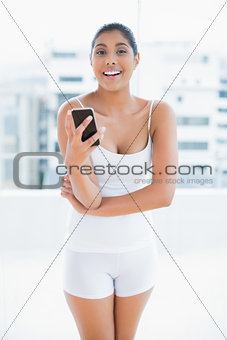 Cheerful toned brunette holding smartphone