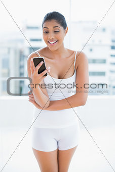 Surprised toned brunette holding smartphone