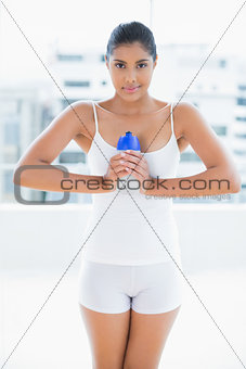 Peaceful toned brunette holding sports bottle