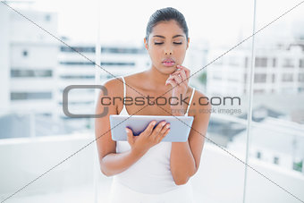 Thoughtful toned brunette using tablet