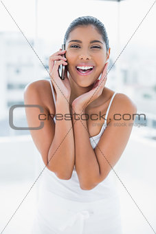 Gleeful toned brunette phoning with mobile phone