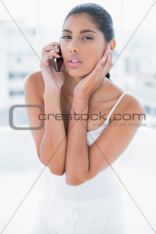 Frowning toned brunette phoning with mobile phone