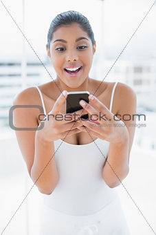 Excited toned brunette holding mobile phone