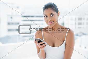 Pleased toned brunette holding mobile phone