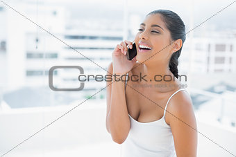 Gleeful toned brunette phoning on mobile phone