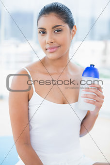 Content toned brunette sitting on floor with sports bottle