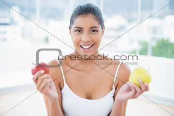 Happy toned brunette holding apples