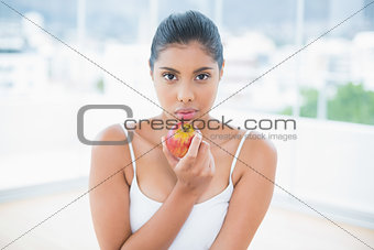 Serious toned brunette holding apple