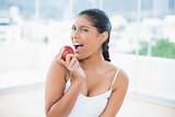 Excited toned brunette holding apple