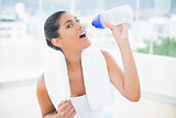 Calm toned brunette with towel holding sports bottle