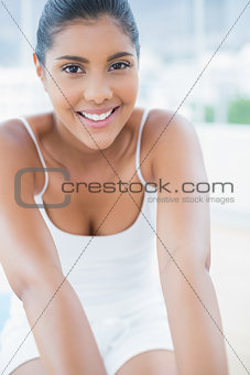 Portrait of smiling toned brunette sitting on floor