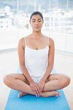 Peaceful toned brunette sitting on floor in lotus pose with closed eyes
