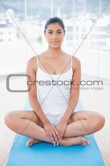 Peaceful toned brunette sitting on floor in lotus pose