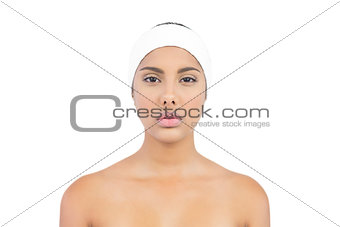 Stern nude brunette with hairband looking at camera