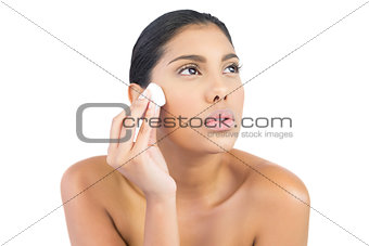 Frowning nude brunette holding cotton ball