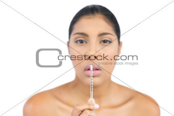 Frowning nude brunette holding a thermometer