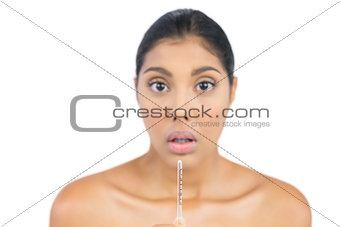 Shocked nude brunette holding a thermometer