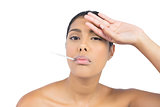 Frowning nude brunette having thermometer in mouth
