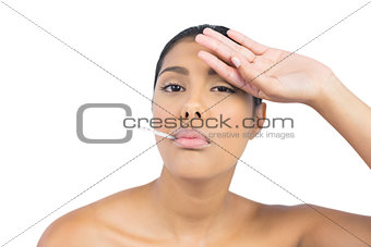 Frowning nude brunette having thermometer in mouth