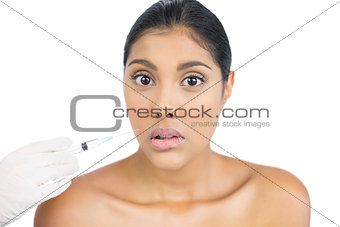 Serious nude brunette holding injection looking at camera