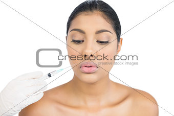 Calm nude brunette holding injection looking down