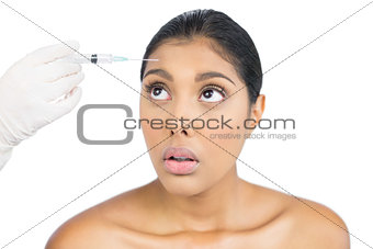 Scared nude brunette holding injection looking up
