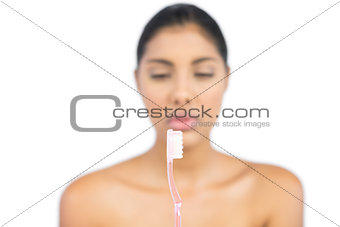 Unsmiling nude brunette holding toothbrush