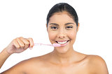Smiling nude brunette using toothbrush