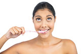 Smiling nude brunette using toothbrush looking up