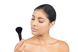 Calm nude brunette holding powder brush