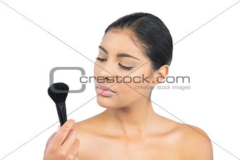 Calm nude brunette holding powder brush