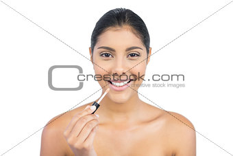 Smiling nude brunette holding lip gloss