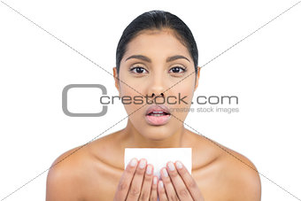 Unsmiling nude brunette holding tissue