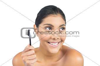 Smiling nude brunette holding eyebrow brush
