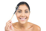 Smiling nude brunette using eyebrow brush