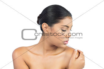 Calm nude brunette turning head holding shoulder
