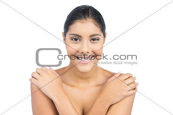 Smiling nude brunette holding shoulders