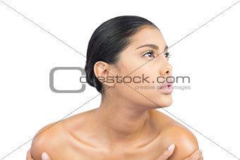 Unsmiling nude brunette holding shoulders looking up