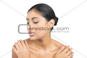 Calm nude brunette holding shoulders with closed eyes