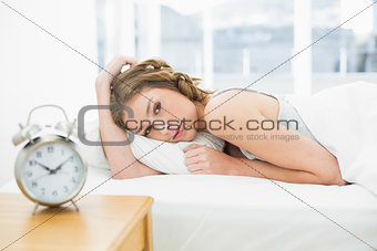 Beautiful tired woman looking at camera lying in her bed