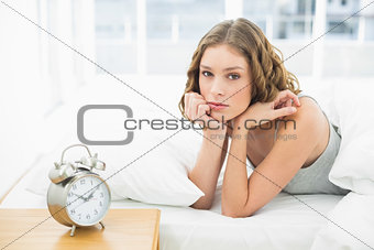 Cute woman lying in her bed looking at camera