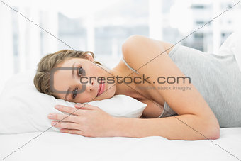 Lovely calm woman lying resting in her bed under the cover