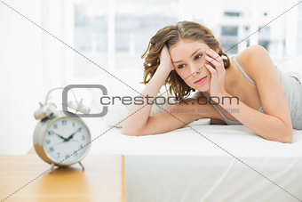 Beautiful day dreaming woman lying in her bed under the cover