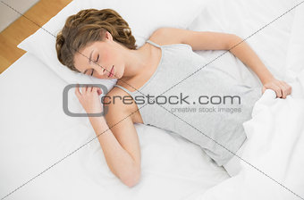 Calm slender woman lying sleeping on her bed under the cover