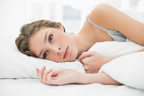 Calm woman lying under the cover on her white bed