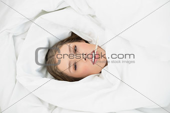 Sick woman lying under the cover on her bed in the bedroom
