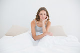 Thoughtful young woman sitting on her bed