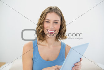 Gorgeous laughing woman holding her tablet while smiling at camera